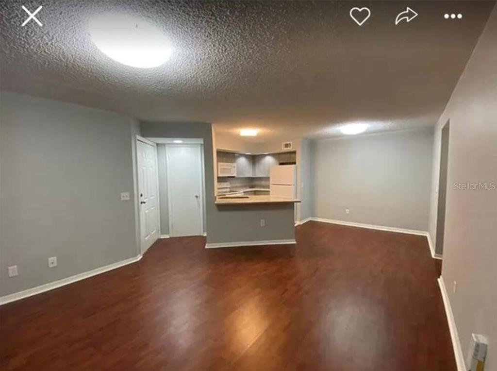 An open-concept living area with wood-look flooring leads to a kitchen with a breakfast bar — 4532 COMMANDER DRIVE UNIT 2122, ORLANDO, FL