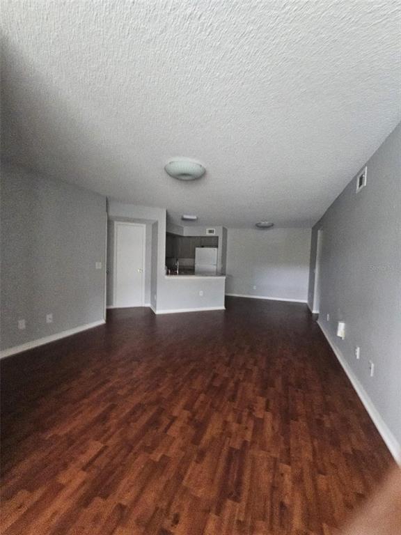 An open-concept living area features wood-look flooring, gray walls, and a view of the kitchen — 4532 COMMANDER DRIVE UNIT 2122, ORLANDO, FL