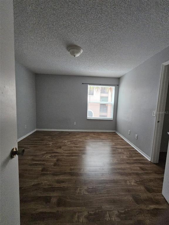 An empty bedroom features light gray walls, wood-look flooring, and a single window — 4532 COMMANDER DRIVE UNIT 2122, ORLANDO, FL