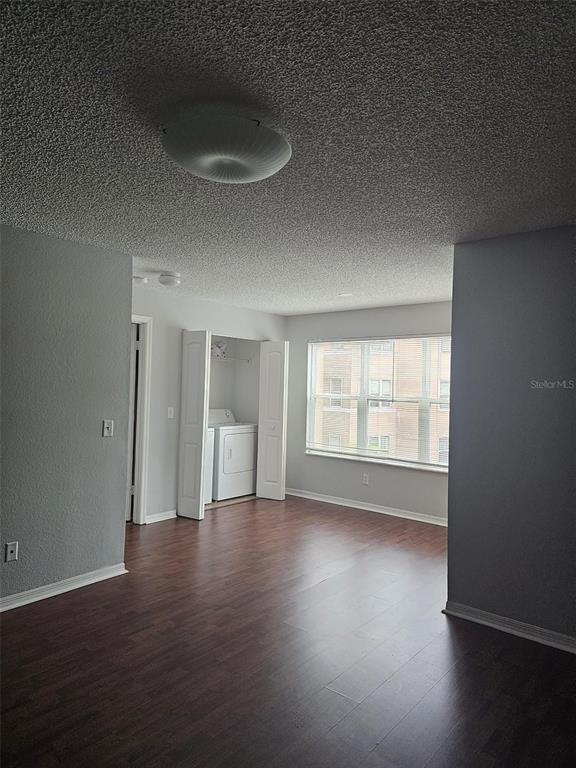 A room with wood-look flooring, a popcorn ceiling, and a closet containing a laundry unit — 4532 COMMANDER DRIVE UNIT 2122, ORLANDO, FL