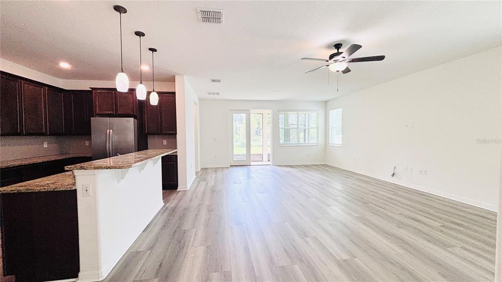 An open-concept kitchen and living area featuring dark wood cabinets, granite countertops, and wood-look flooring — 557 SCOTT LAKE CREEK LANE, LAKELAND, FL