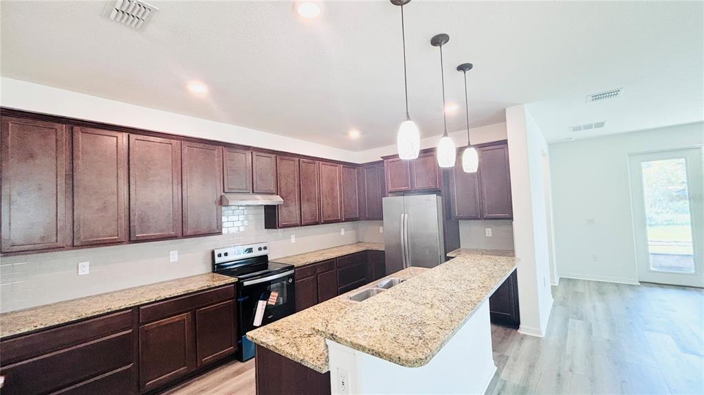 A kitchen features dark wood cabinets, granite countertops, stainless steel appliances, and a breakfast bar — 557 SCOTT LAKE CREEK LANE, LAKELAND, FL