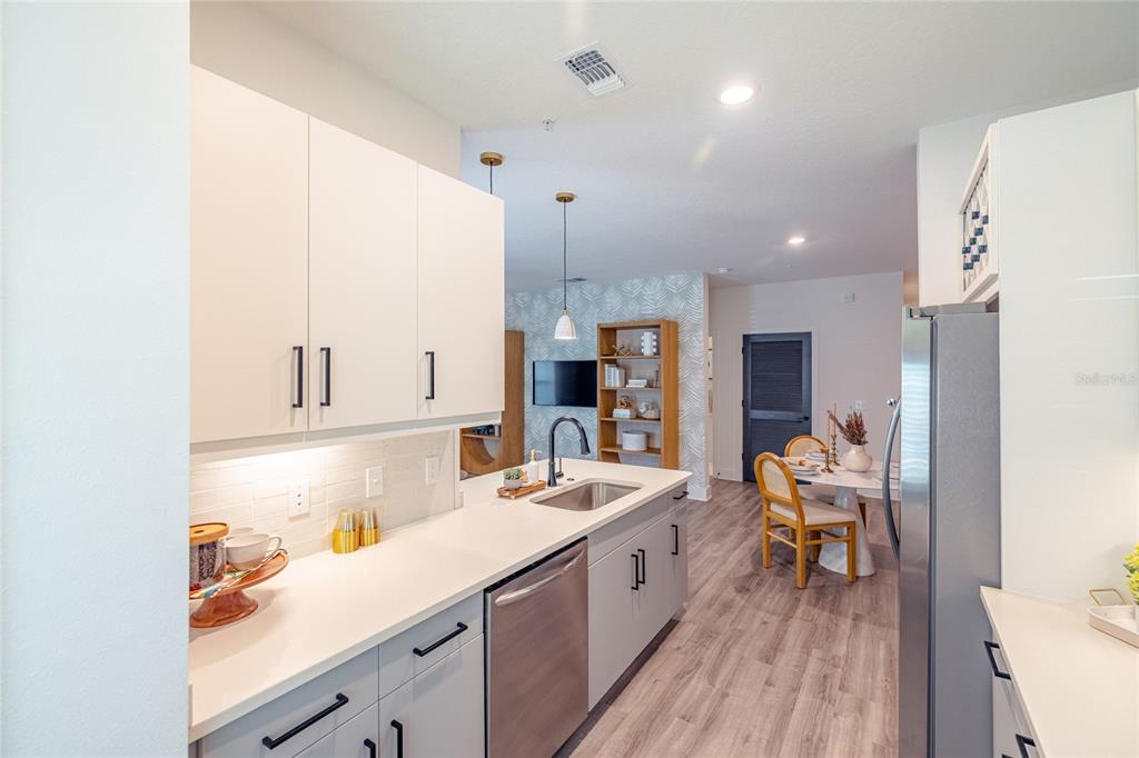 A modern kitchen features white upper cabinets, light gray lower cabinets, and stainless steel appliances — 1420 LAKEFRONT DRIVE UNIT 1208, SARASOTA, FL