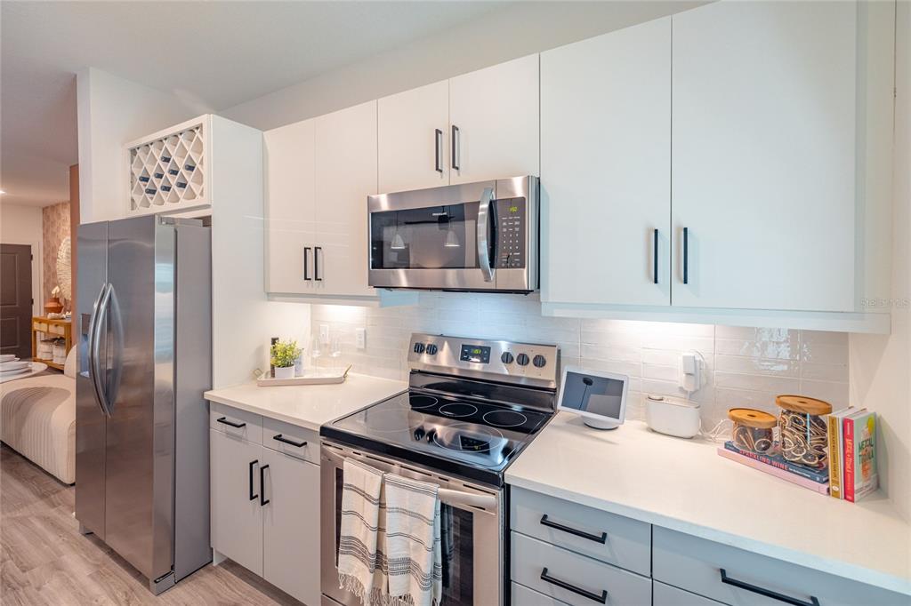 A modern kitchen features white cabinets, stainless steel appliances, and light-colored countertops — 1420 LAKEFRONT DRIVE UNIT 1208, SARASOTA, FL