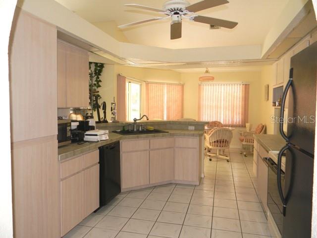 A kitchen with light wood cabinets, white tile floors, and a ceiling fan — 212 BOA VISTA STREET, PUNTA GORDA, FL