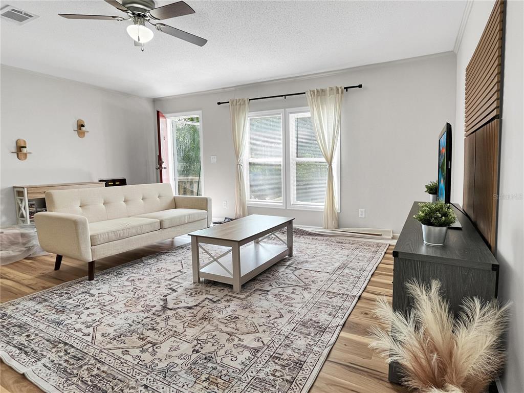 A living room features a beige sofa, a coffee table, and a television on a stand — 276 NW BATTLE HILL LANE, LAKE CITY, FL
