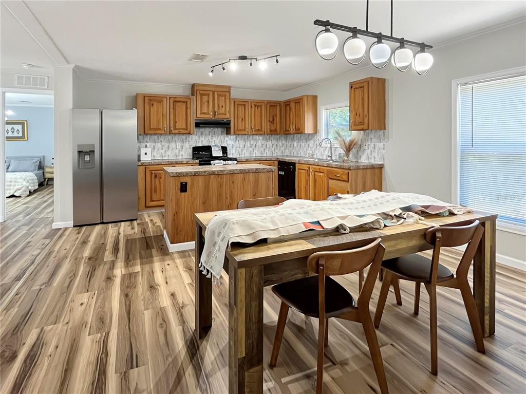 A kitchen with wood cabinets and a dining area with a wooden table and chairs — 276 NW BATTLE HILL LANE, LAKE CITY, FL
