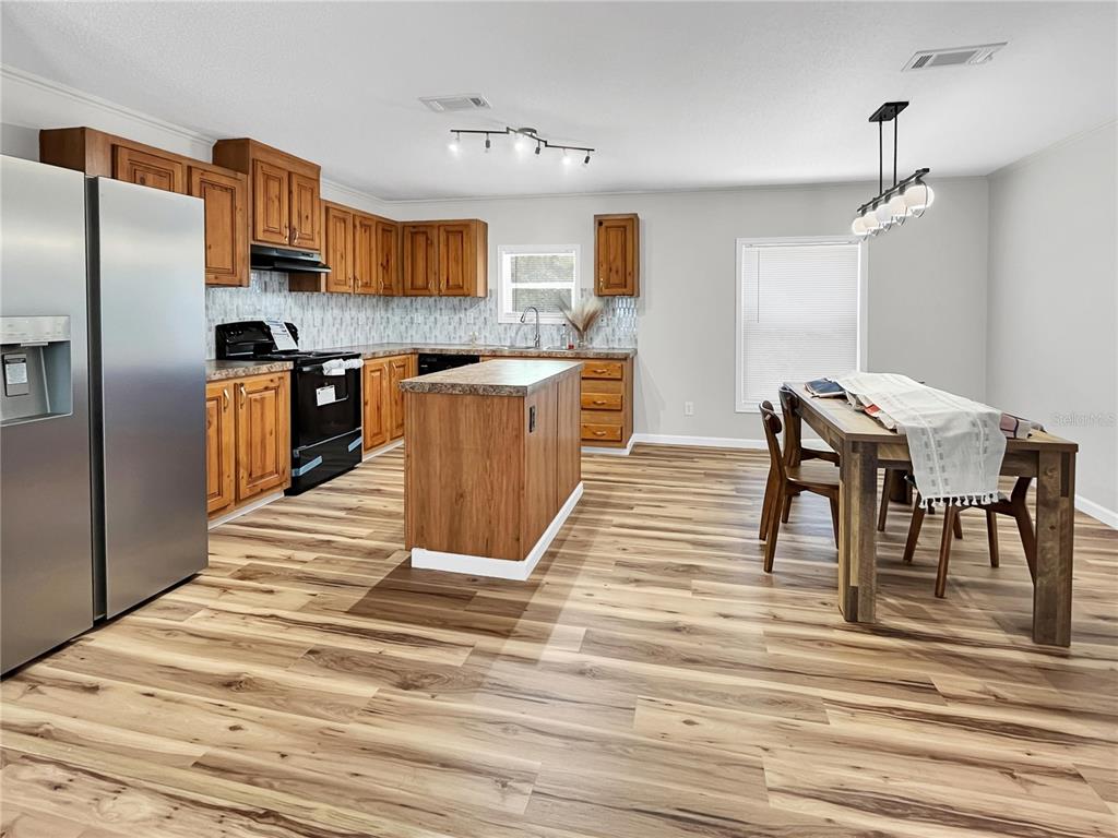 A kitchen with wood cabinets, a center island, and stainless steel appliances on wood-look flooring — 276 NW BATTLE HILL LANE, LAKE CITY, FL