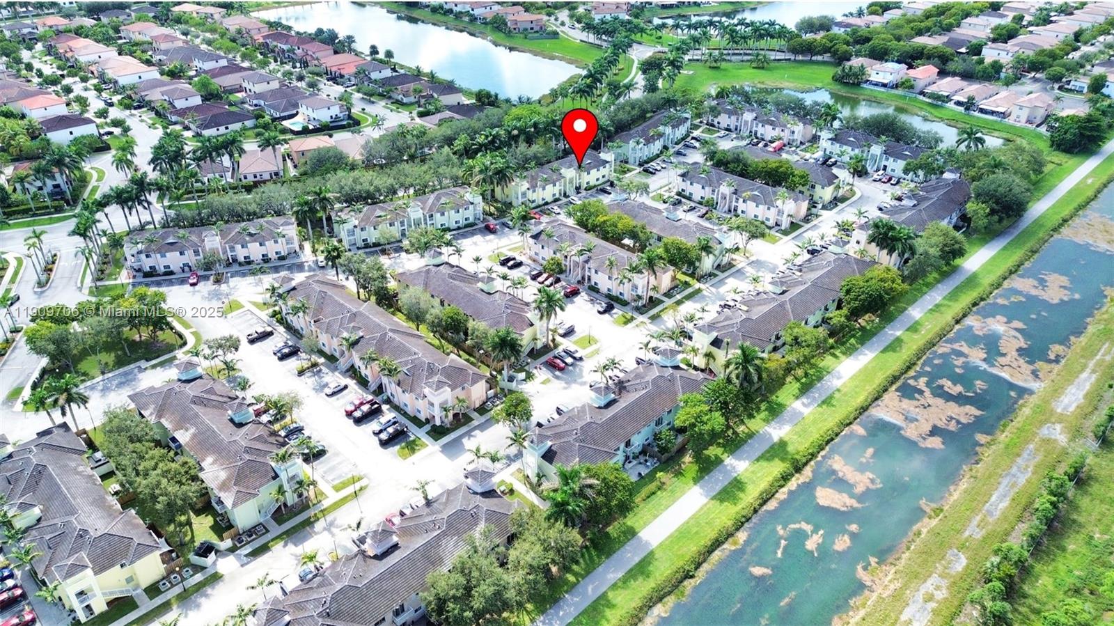 An aerial view shows a multi-family residential complex with parking lots and a nearby canal — 2610 NE 3rd Dr # 203, Homestead FL 33033, HOMESTEAD, FL