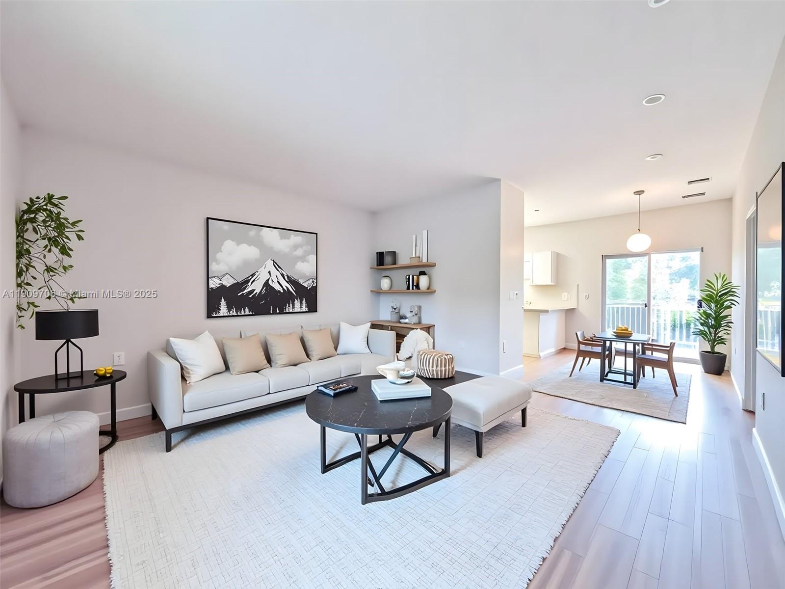 A living room with a sofa, coffee table, and dining area featuring light wood floors — 2610 NE 3rd Dr # 203, Homestead FL 33033, HOMESTEAD, FL