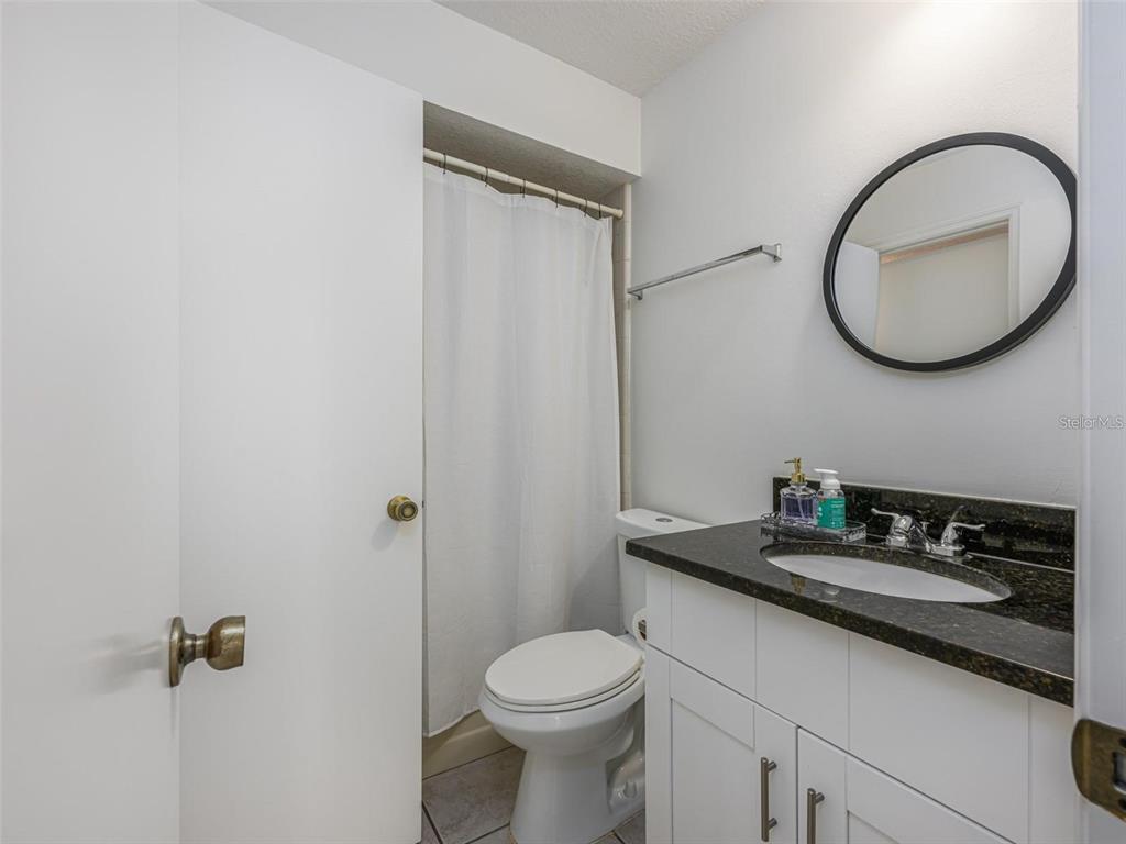 A bathroom features a white vanity with a dark countertop, a toilet, and a shower — 2383 SUN VALLEY CIRCLE UNIT 2383, WINTER PARK, FL