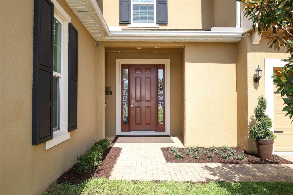 The front exterior of a house features a red door, brick walkway, and landscaping — 1329 WILDCAT LANE, MINNEOLA, FL