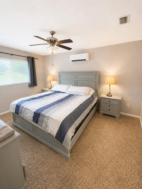 A bedroom features a gray bed frame, a ceiling fan, and a wall-mounted air conditioner — 2746 MENDELIN STREET, APOPKA, FL