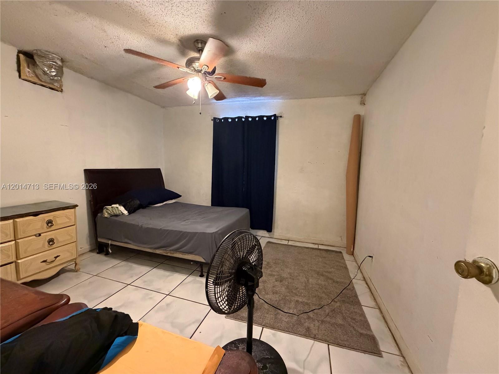 A bedroom features a bed, a dresser, a ceiling fan, and tile flooring — 385 NE 129th St, North Miami FL 33161, NORTH MIAMI, FL