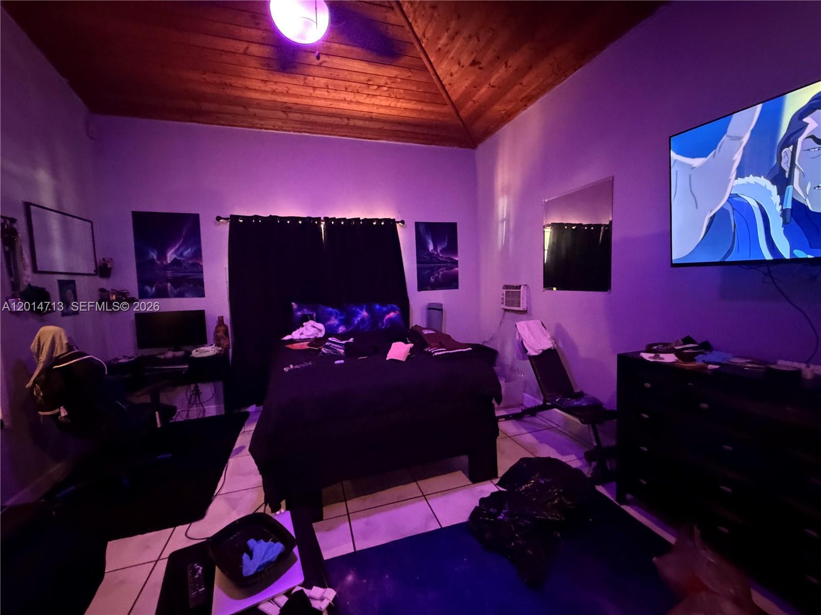 A bedroom features a wooden vaulted ceiling, purple ambient lighting, a bed, and a television — 385 NE 129th St, North Miami FL 33161, NORTH MIAMI, FL