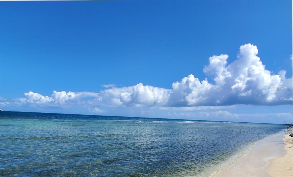 A view of a sandy beach meeting the clear blue ocean under a cloudy sky — 8C BARRIO FRAILES, CULEBRA, PR