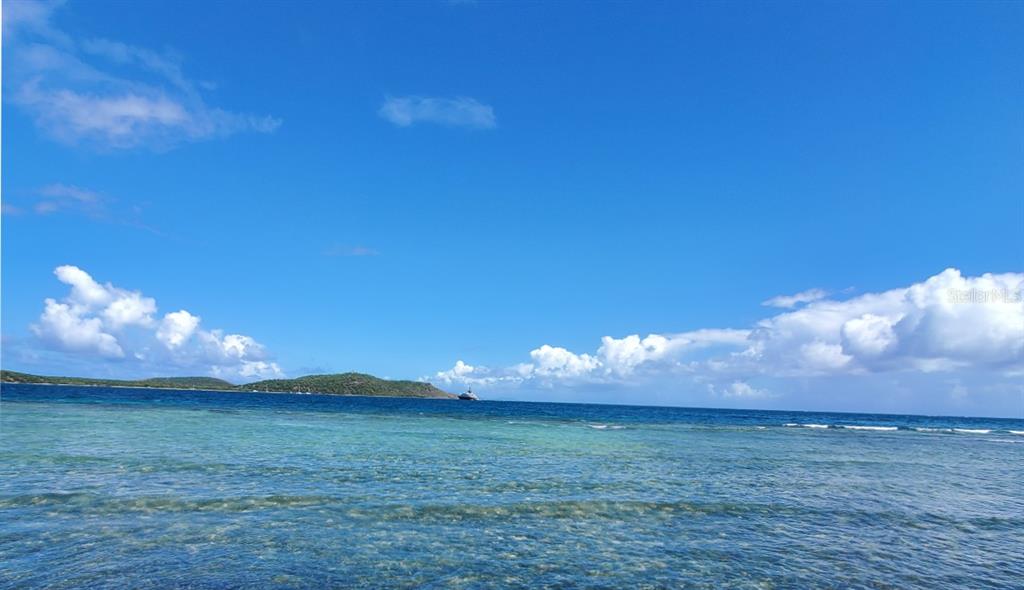 A view of a shallow turquoise ocean with a distant island under a blue sky — 8C BARRIO FRAILES, CULEBRA, PR