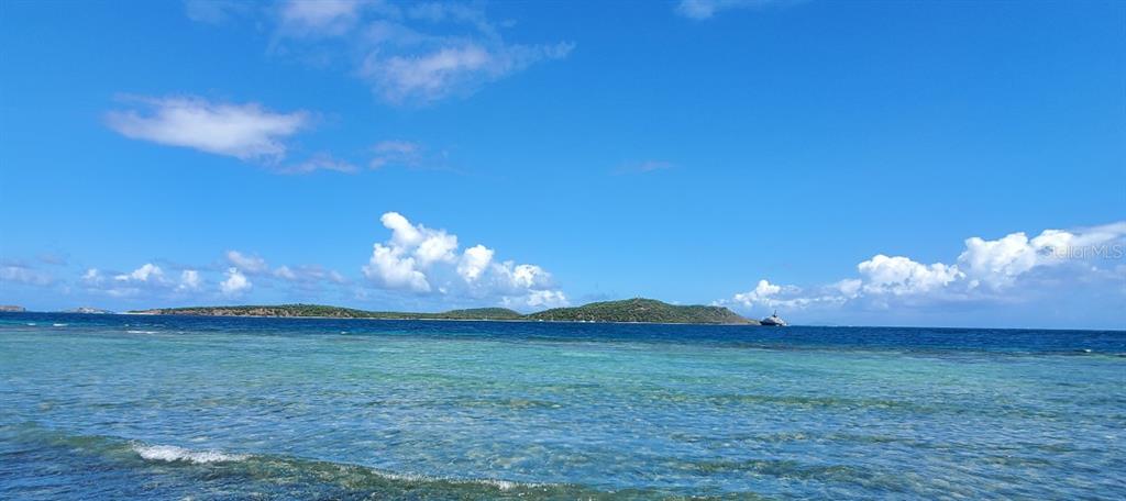 A view of the ocean with a distant island and a boat under a blue sky — 8C BARRIO FRAILES, CULEBRA, PR