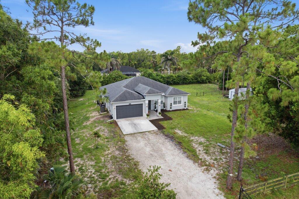An aerial view of a single-story house with a gray roof and a gravel driveway — 18310 42nd Road N, FL 33470, FL