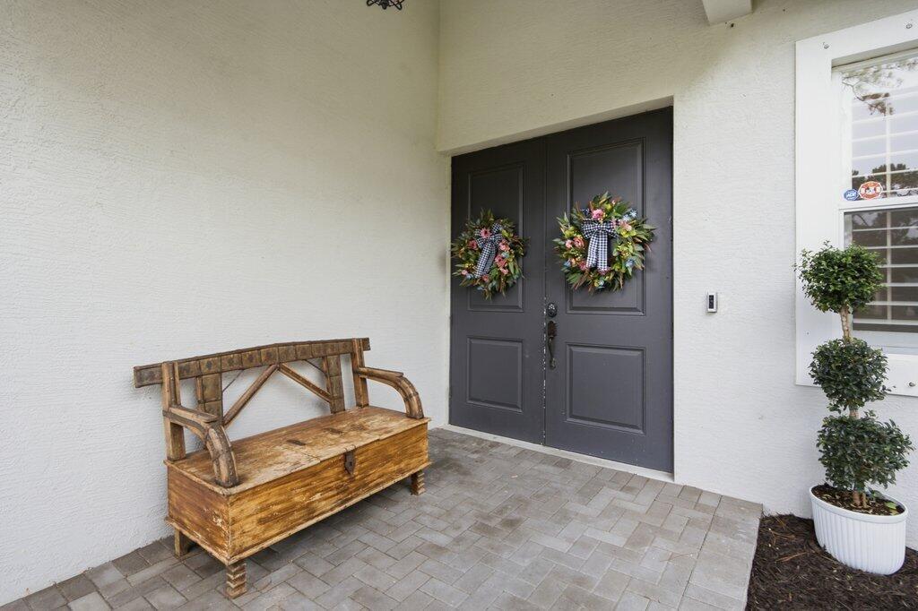 A wooden bench sits on a paved porch in front of dark double entry doors — 18310 42nd Road N, FL 33470, FL