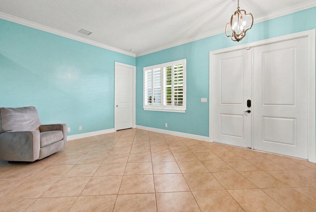 An entryway with light blue walls, tile flooring, a gray armchair, and white double doors — 18310 42nd Road N, FL 33470, FL