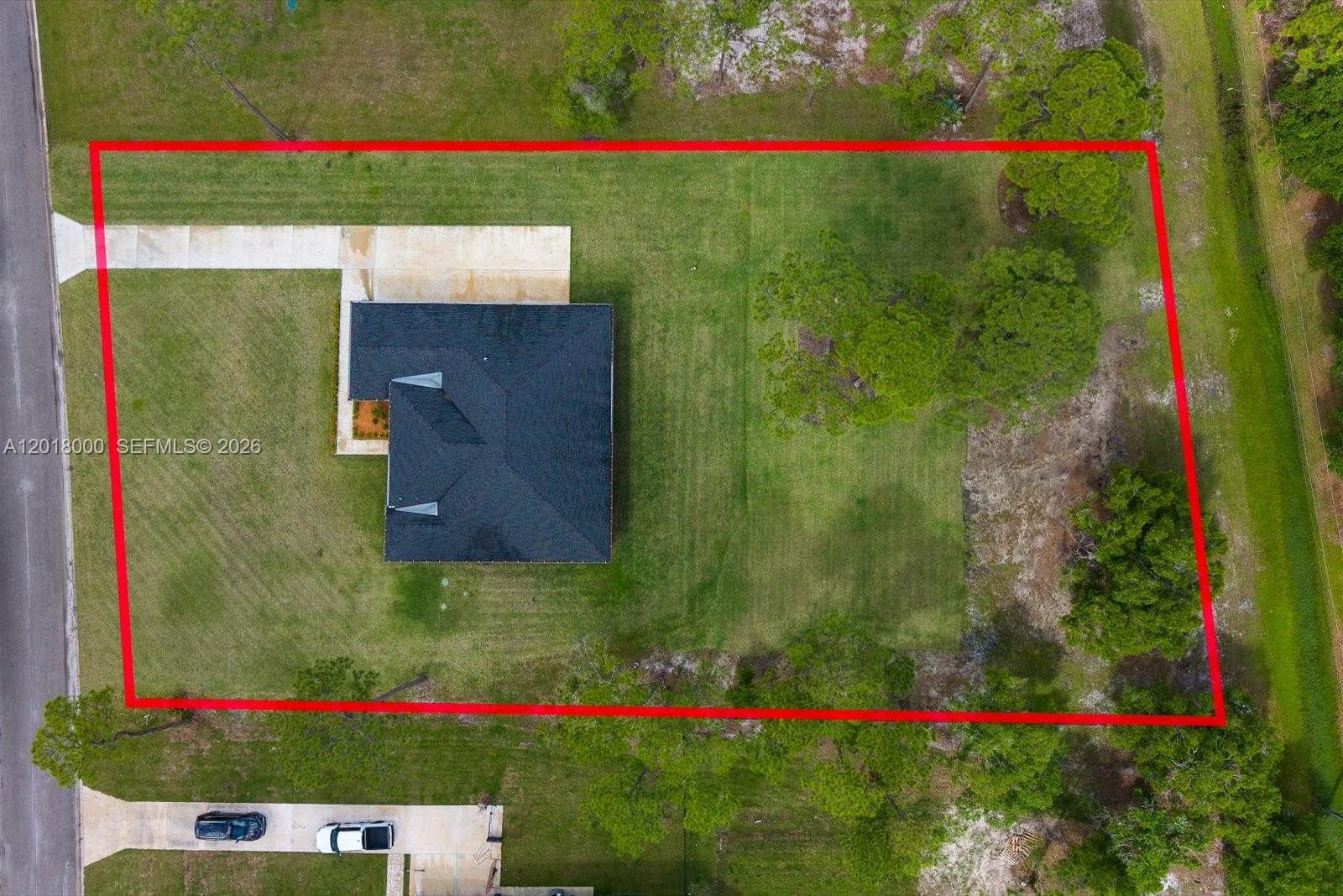 An aerial view shows a house with a dark roof centered on a grassy lot — 10630 Sugar Pine Dr, Fort Pierce FL 34945, FORT PIERCE, FL