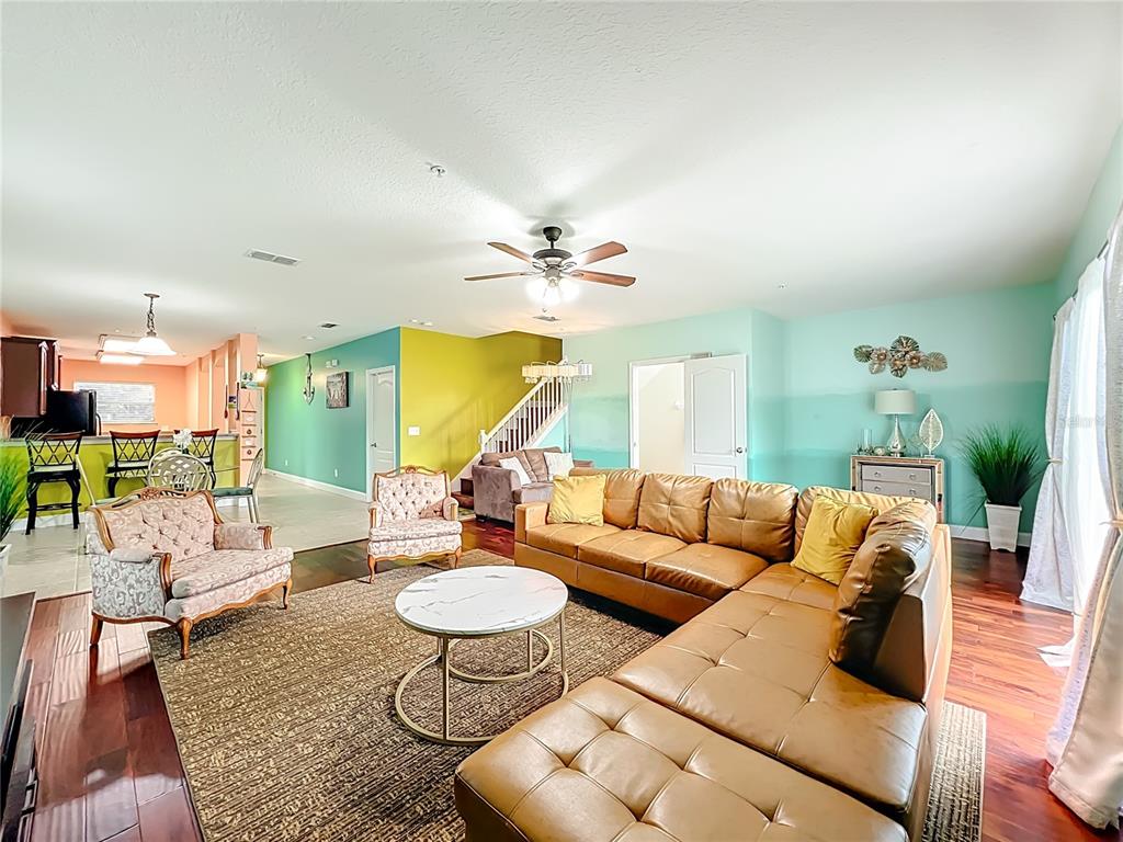 A living room features a large leather sectional, patterned armchairs, and colorful accent walls — 10100 GREEN BRANCH COURT, ORLANDO, FL