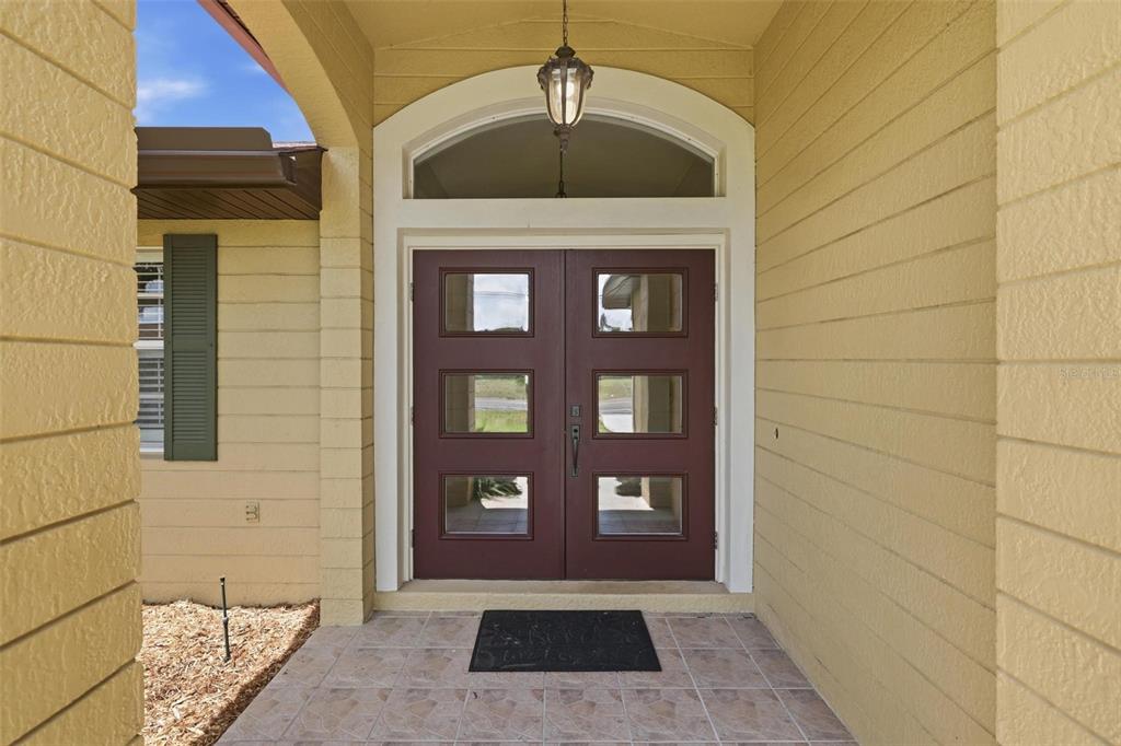A double front door with six glass panels is set within a covered entryway — 894 BOUNDARY BOULEVARD, ROTONDA WEST, FL