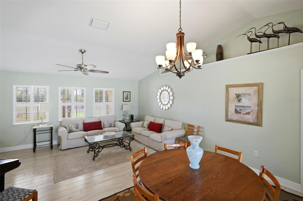 A living and dining area features light green walls, a chandelier, and light wood flooring — 894 BOUNDARY BOULEVARD, ROTONDA WEST, FL