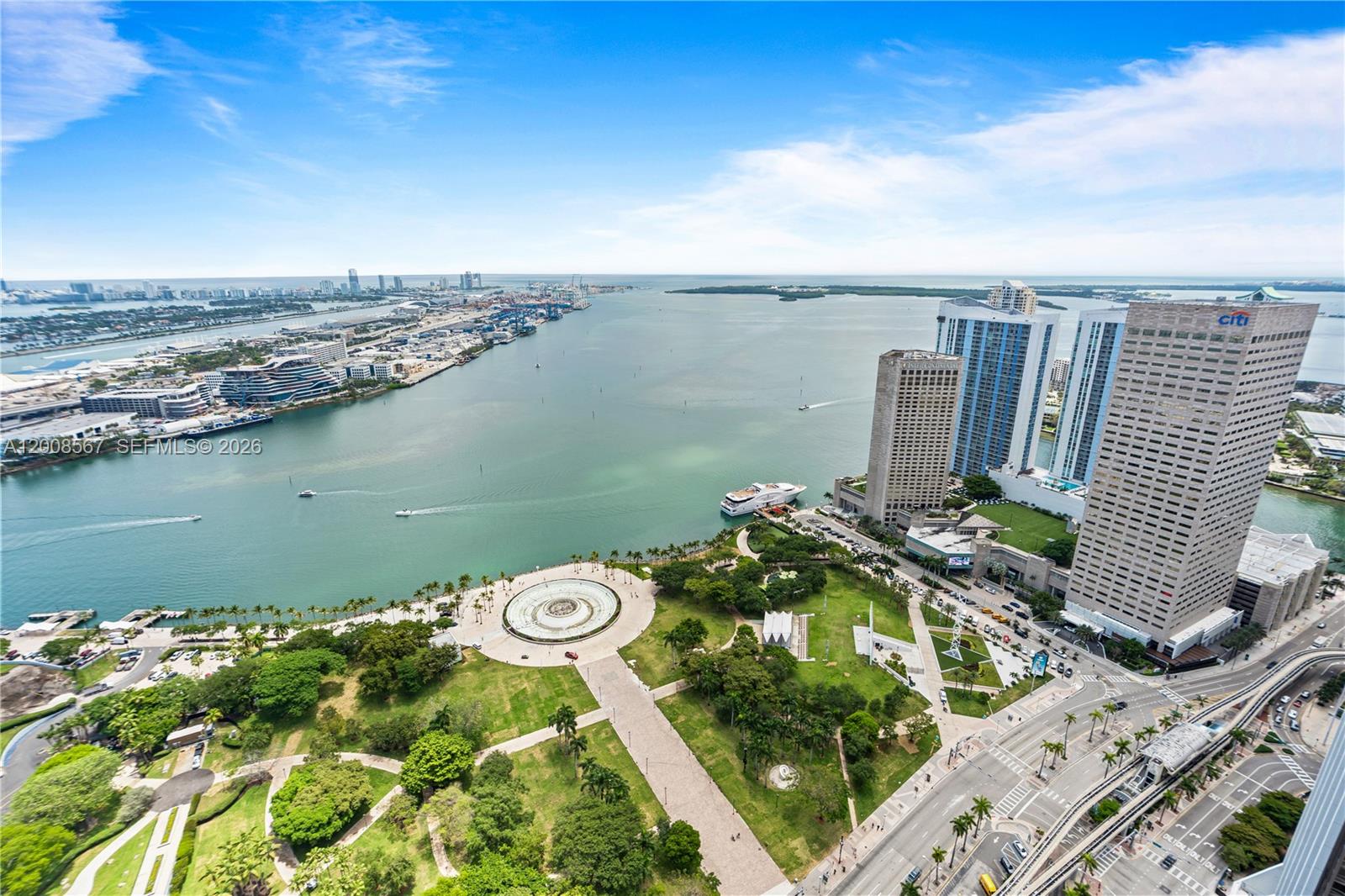 An aerial view shows a park with a circular fountain overlooking a bay and skyscrapers — 50 Biscayne Blvd # 5402, Miami FL 33132, MIAMI, FL