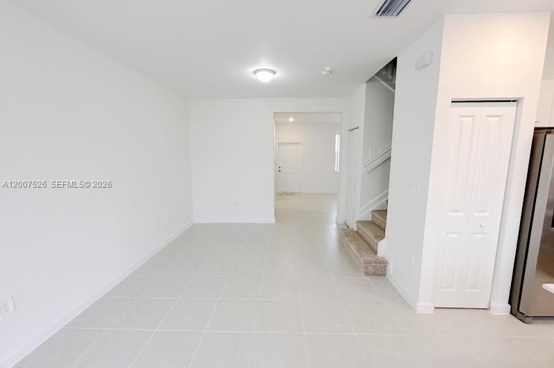 An interior view shows a tiled room with a staircase, a closet, and a doorway — 12428 NW 23rd Ct, Miami FL 33167, MIAMI, FL