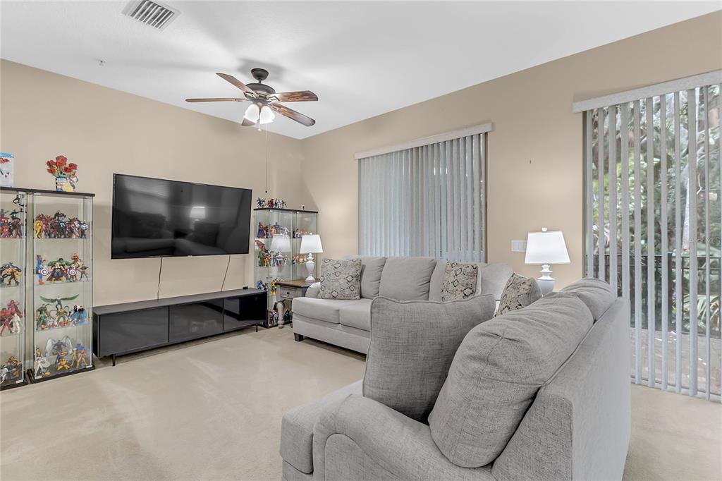 A living room features a sectional sofa, a wall-mounted television, and glass display cabinets — 572 PINEBRANCH CIRCLE, WINTER SPRINGS, FL