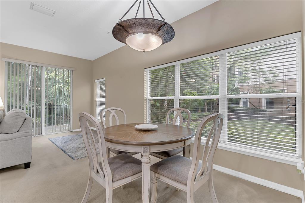 A dining area features a round wooden table, four chairs, and large windows with blinds — 572 PINEBRANCH CIRCLE, WINTER SPRINGS, FL