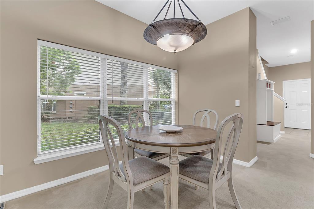 A dining area features a round wooden table, four chairs, and a hanging light fixture — 572 PINEBRANCH CIRCLE, WINTER SPRINGS, FL