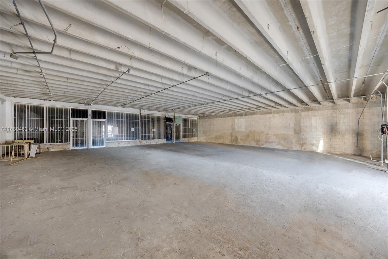An empty, unfinished commercial space features exposed concrete ceilings, block walls, and barred windows — 1554 W Flagler St, Miami FL 33135, MIAMI, FL