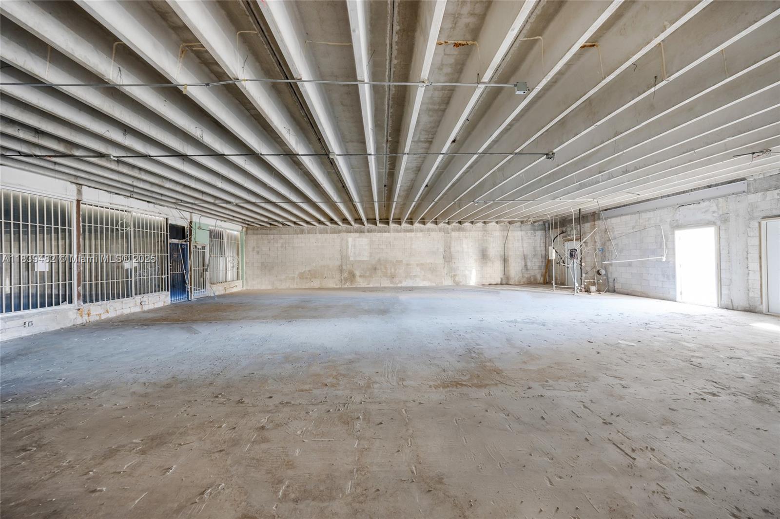 An unfinished commercial space features exposed concrete block walls, a ribbed ceiling, and concrete flooring — 1554 W Flagler St, Miami FL 33135, MIAMI, FL
