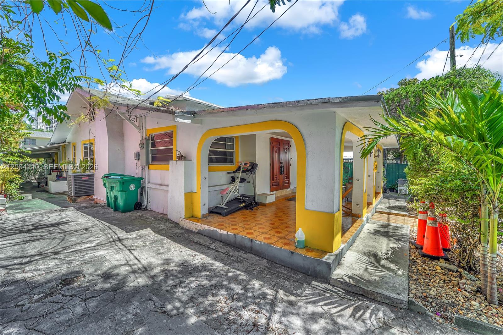 A single-story house with a yellow-trimmed porch, a treadmill, and a concrete driveway — 219 SW 6th Ave, Miami FL 33130, MIAMI, FL