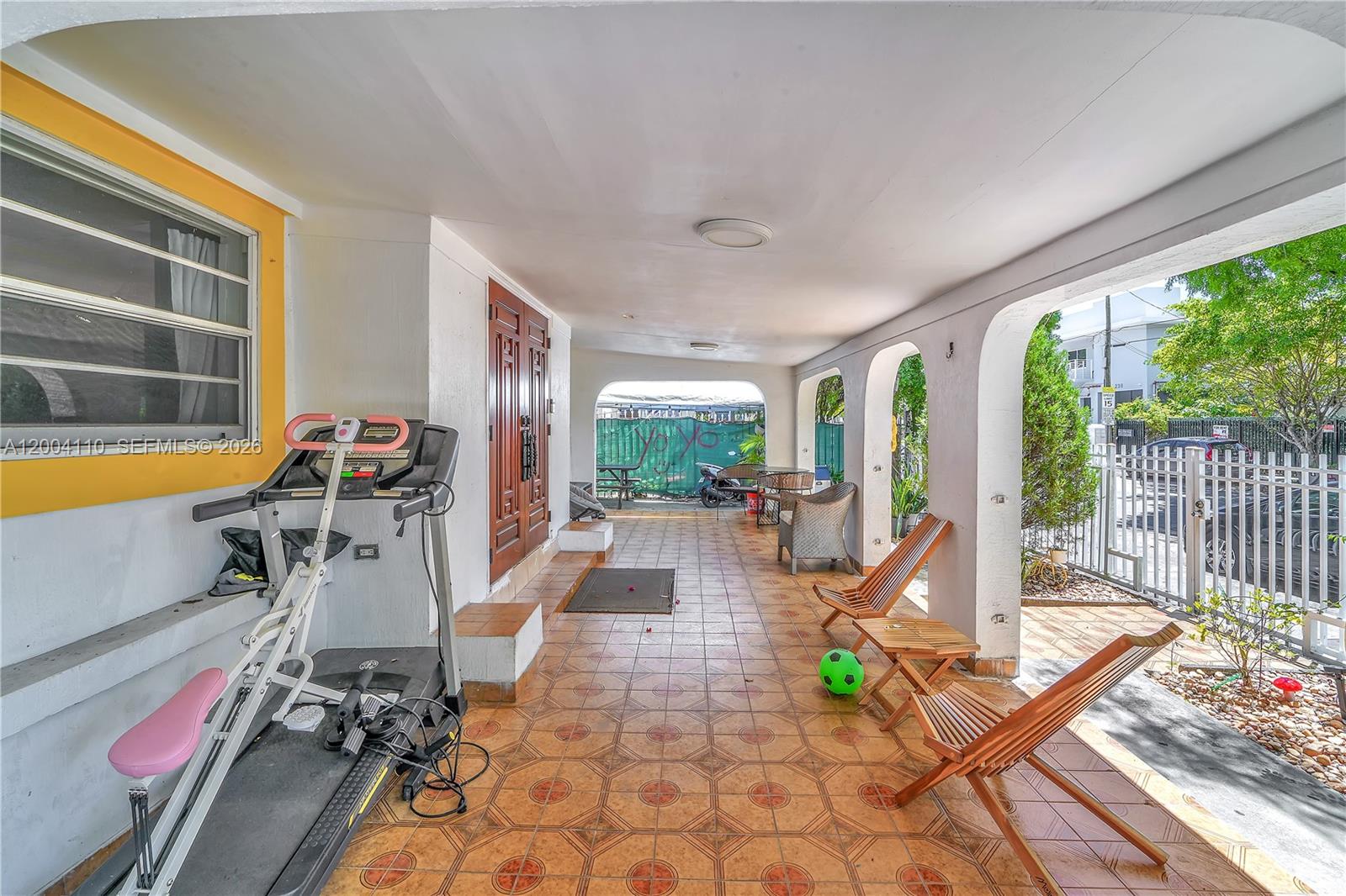 A covered patio features tiled flooring, arched openings, a treadmill, and wooden lounge chairs — 219 SW 6th Ave, Miami FL 33130, MIAMI, FL
