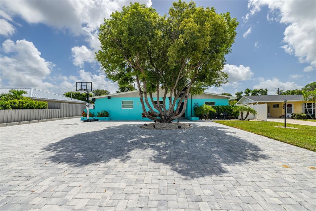 A bright turquoise house features a large tree in the center of a paved driveway — 3407 29TH STREET W, BRADENTON, FL