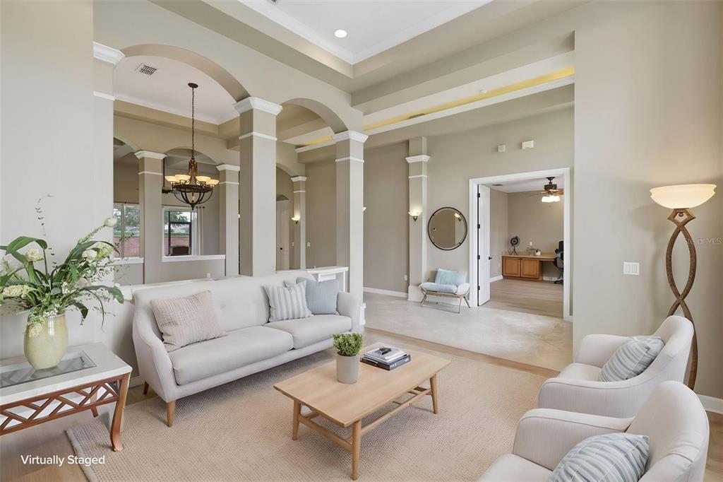 A spacious foyer features light wood flooring, arched architectural columns, and a central glass-topped table — 426 DUFF DRIVE, WINTER GARDEN, FL