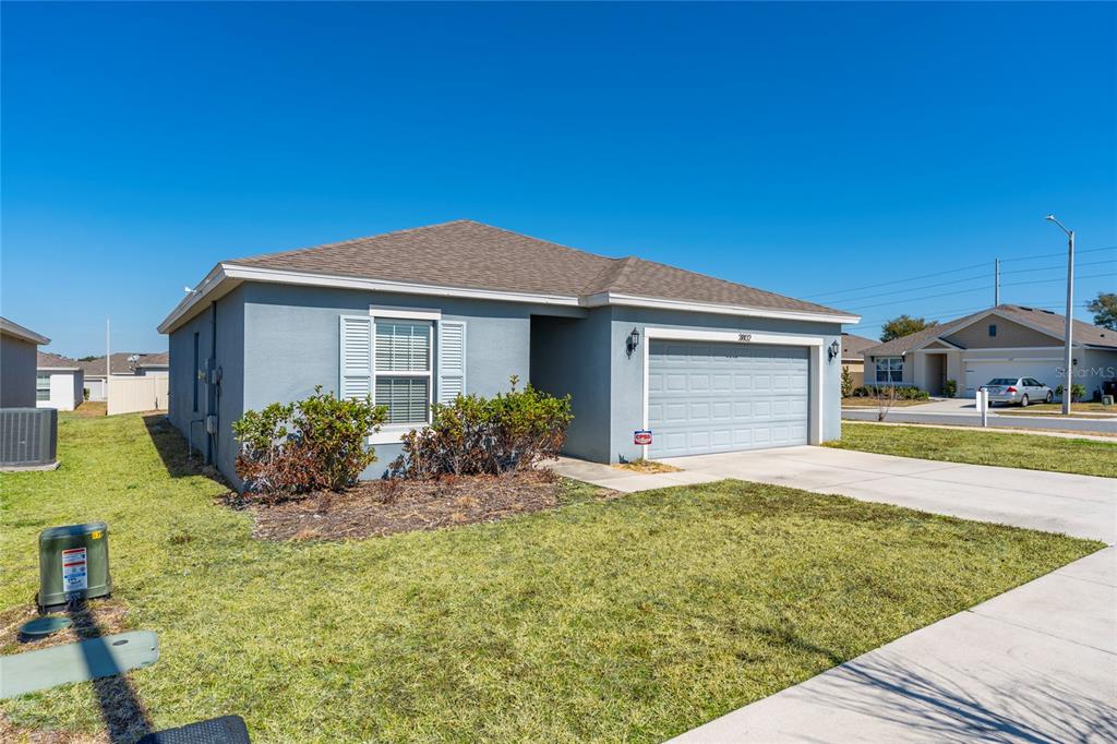 A single-story blue house with a two-car garage and a front lawn — 3802 WHITNEY WAY, HAINES CITY, FL