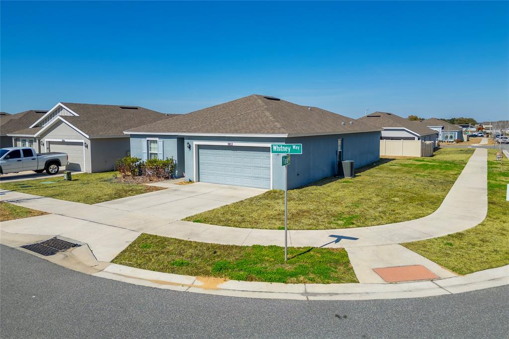 A single-story house with a gray exterior and a two-car garage on a corner lot — 3802 WHITNEY WAY, HAINES CITY, FL