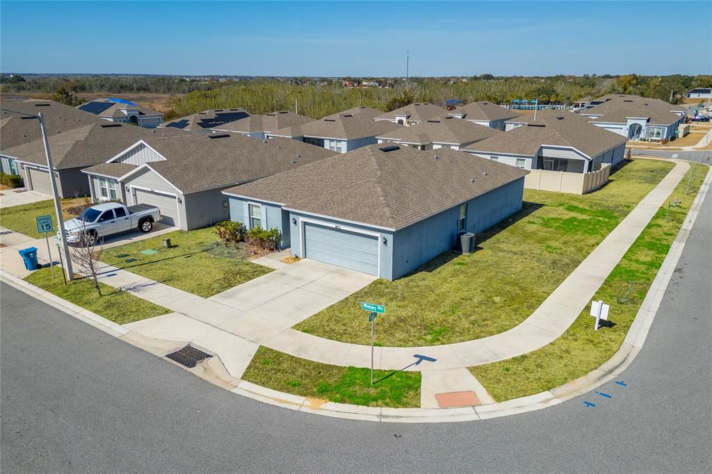 An aerial view of a suburban corner lot featuring a single-story house with a garage — 3802 WHITNEY WAY, HAINES CITY, FL