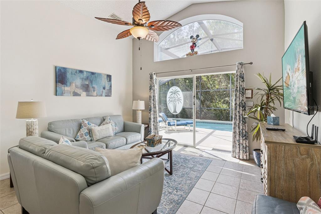 A living room features a vaulted ceiling, a ceiling fan, and sliding doors to a pool — 138 MADIERA BEACH BOULEVARD, KISSIMMEE, FL