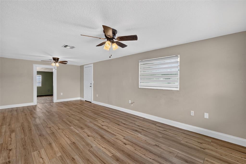 An empty room with wood-look flooring, two ceiling fans, and a window with blinds — 1111 DORA AVENUE, TAVARES, FL
