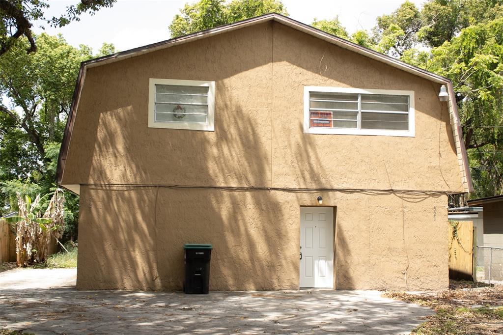 A two-story tan stucco building with a gambrel roof, two windows, and a white door — 621 W SOUTH STREET, ORLANDO, FL