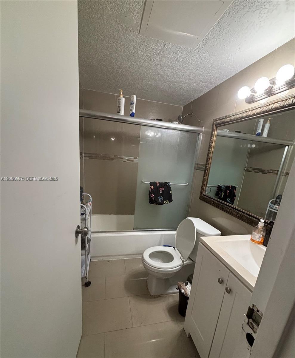 A bathroom features a white vanity, a toilet, and a shower-tub combination with sliding doors — 16450 NW 2nd Ave # 109, Miami FL 33169, MIAMI, FL
