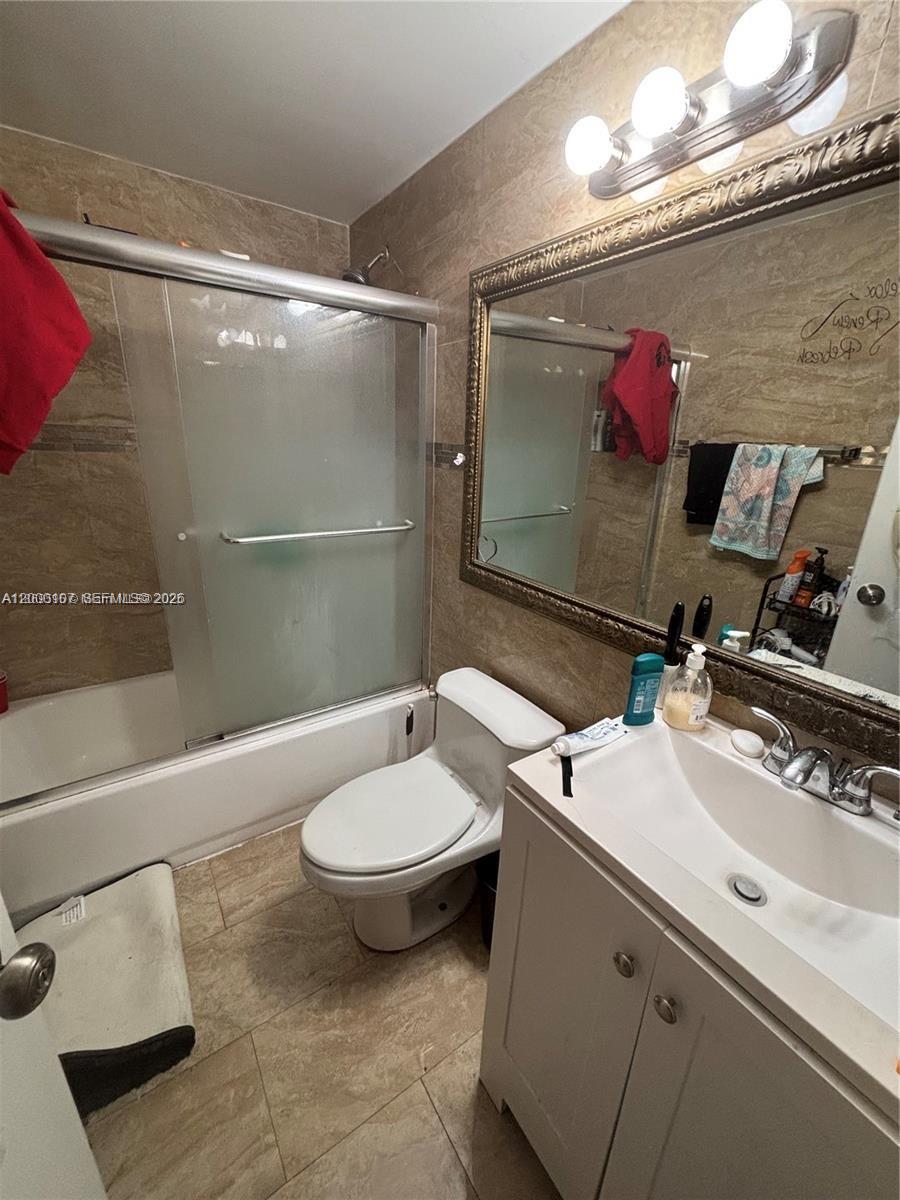 A bathroom features a tiled shower-tub combo, a white vanity, and a toilet — 16450 NW 2nd Ave # 109, Miami FL 33169, MIAMI, FL