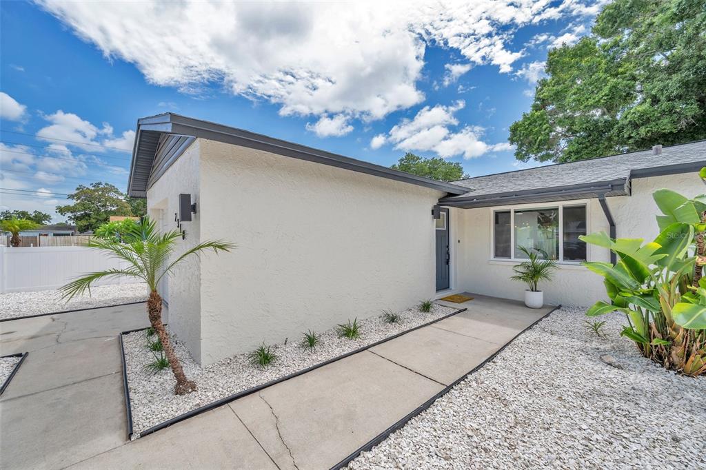 A single-story house with white stucco walls, a gray roof, and a gravel front yard — 2310 MARY SUE STREET, LARGO, FL