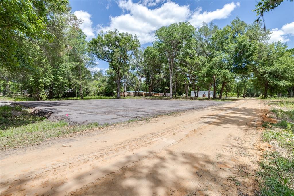 A dirt road runs alongside a cleared, leveled lot surrounded by mature trees — SE 124TH AVENUE, WEBSTER, FL